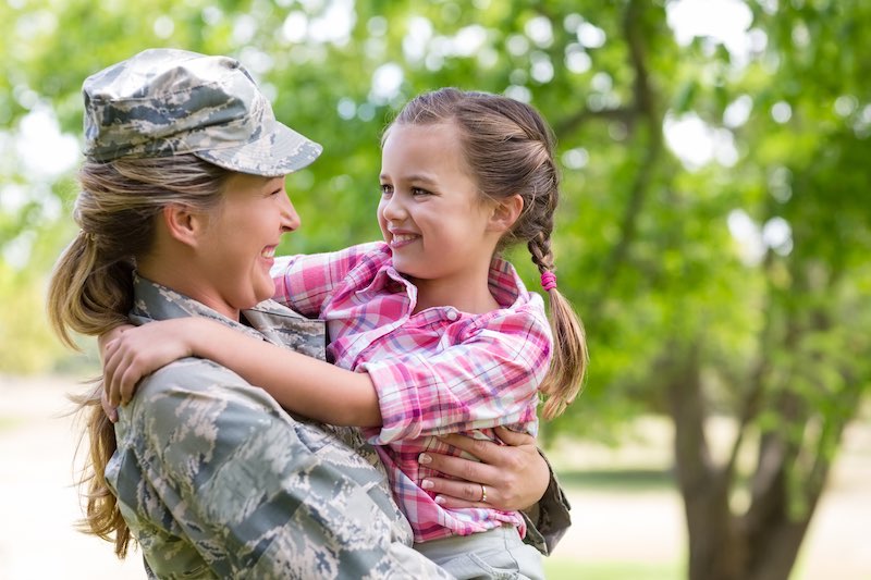 Happy female soldier with her daughter in park on a sunny day